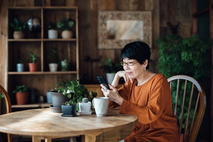 Person sitting at a table looking at a phone.