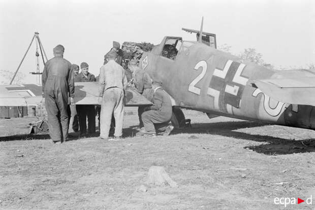 Истребитель Мессершмитт Bf.109 из третьей группы 52-ой истребительной эскадры и обслуживающий технический персонал Истребитель Мессершмитт Bf.109 из третьей группы 52-ой истребительной эскадры и обслуживающий технический персонал
