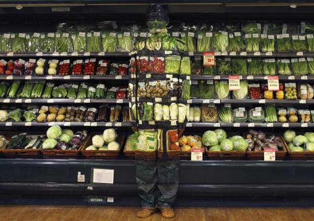 Artist Liu Bolin demonstrates an art installation by blending in with vegetables displayed on the shelves at a supermarket in Beijing on November 10, 2011. (REUTERS / China Daily)