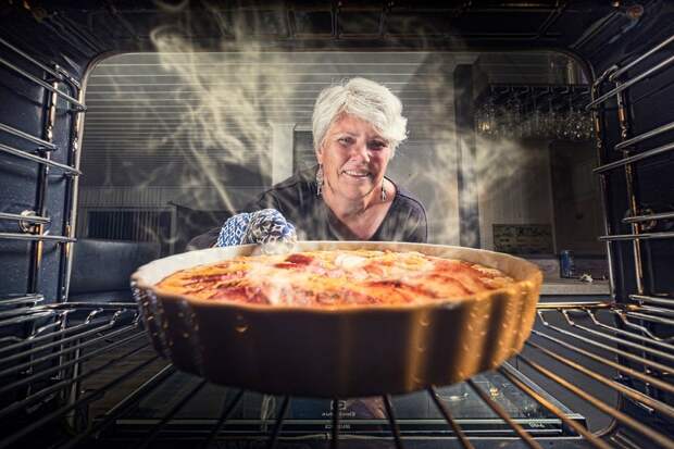 Женщина ставит пирог в духовку