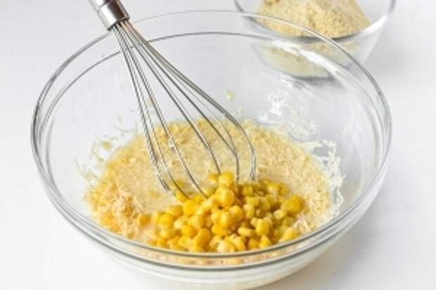 С консервированной кукурузы сливаем жидкость и добавляем зёрна к яично-сырной смеси. Аккуратно перемешиваем.