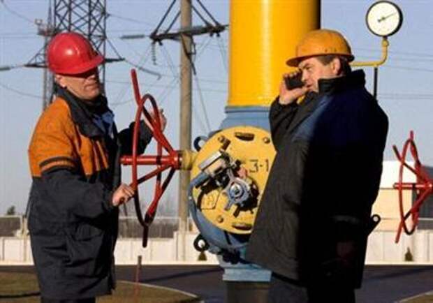 FILE PHOTO: A worker turns a valve as another worker talks on a phone at a gas compressor station at the Yamal-Europe pipeline near Nesvizh, some 130 km (81 miles) southwest of Minsk, Belarus, December 29, 2006. REUTERS/Vasily Fedosenko/File Photo
