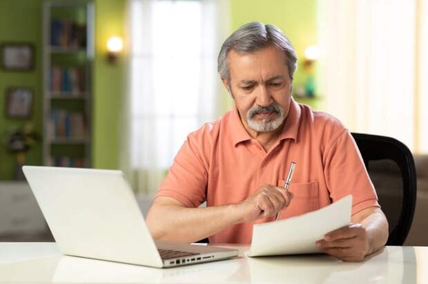 Person holding pen and looking at document.