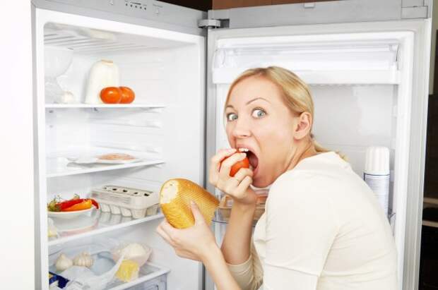 Женщина ест  из холодильника