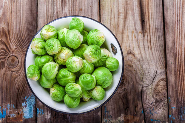 Fresh organic Brussels sprouts in a bowl on a wooden table