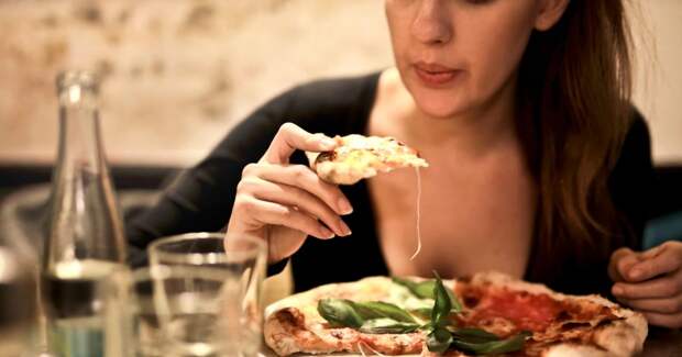 Женщина аппетитно кушает пиццу. Прямо кусает ломоть за ломтем. А-а-а-а... прямо пиццы хочется!