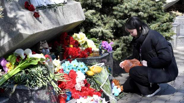 Люди несут цветы и свечи к стихийному мемориалу у «Крокуса»