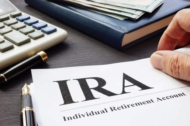 Informational brochure about IRAs on a desk, surrounded by pens, a calculator, and a journal.