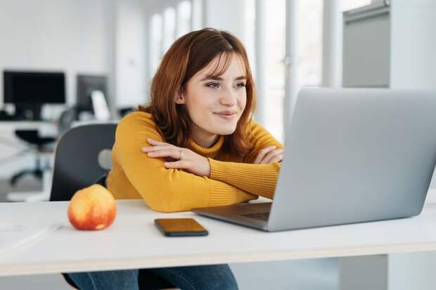 A smiling person at a laptop.