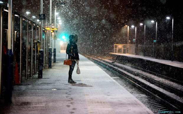 Пассажирка ждёт прибытия пригородного поезда на железнодорожной станции «Эрлсфиелд» во время снегопада.