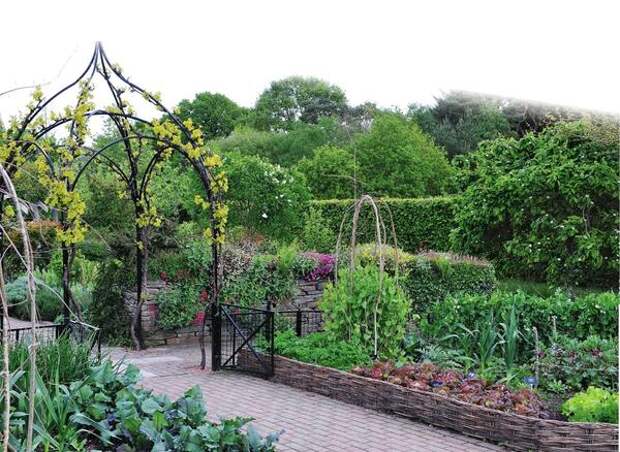 Ажурная металлическая арка служит стильной границей между декоративной и огородной зонами сада.