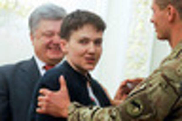 Ukrainian President Petro Poroshenko,  left, smiles, as Ukrainian jailed pilot Nadezhda Savchenko, center is congratulated by servicemen of the Aidar battalion, in the Presidential Office in Kiev, Ukraine, Wednesday, May 25, 2016. Russia has released jailed pilot Nadezhda Savchenko, as part of a swap for two Russian servicemen imprisoned in Ukraine. (AP Photo/Efrem Lukatsky)