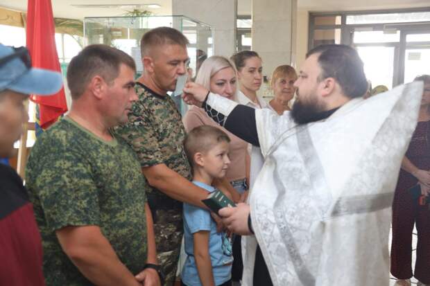 Священник благословляет группу людей.