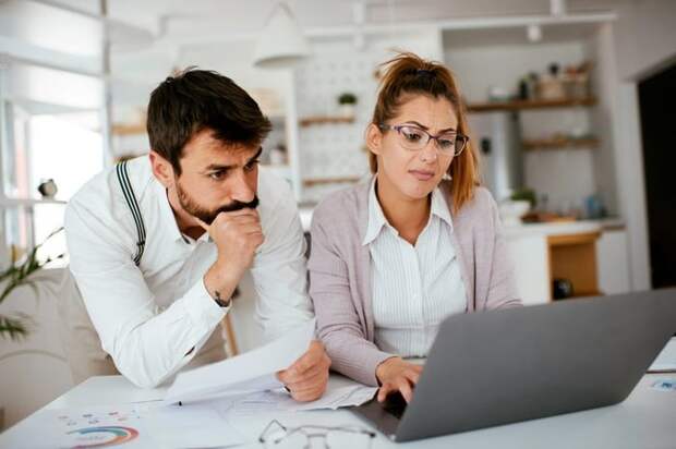 Young couple skeptically looks at information on a laptop screen