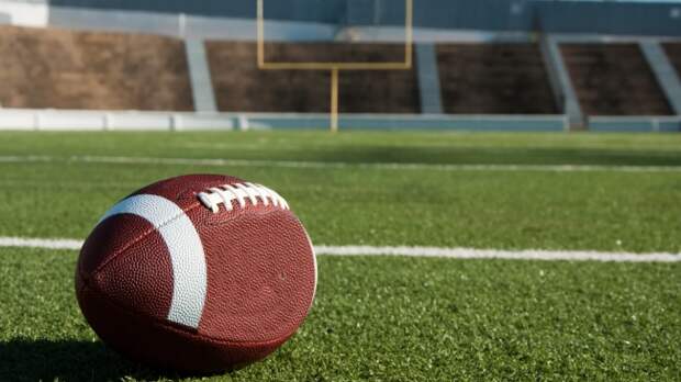 A football sits on the field with uprights in the background.