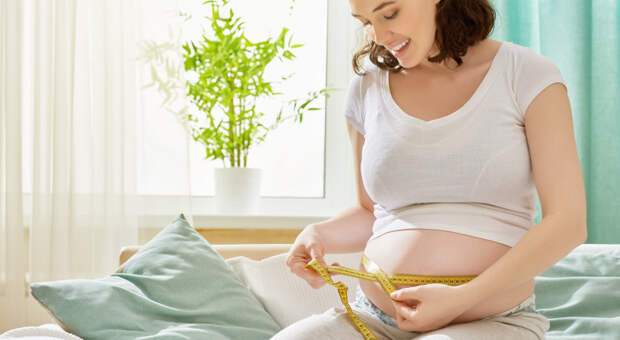 беременная женщина измеряет живот