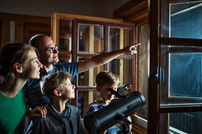 Family looking at the night sky through a telescope.
