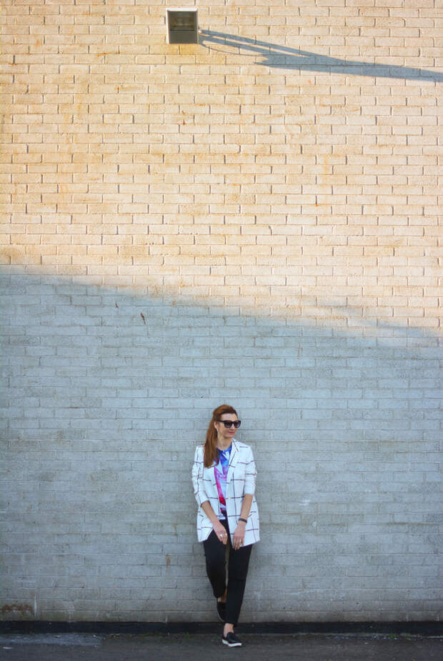 Mixed patterns: Windowpane check coat, graphic t-shirt, black trousers and slip on sneakers