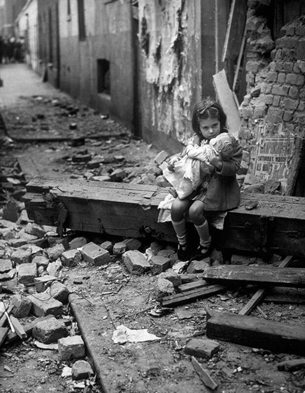 Маленькая девочка с плюшевым зайцем, сидит на развалинах своего разбомбленного дома, Лондон, 1940 г.