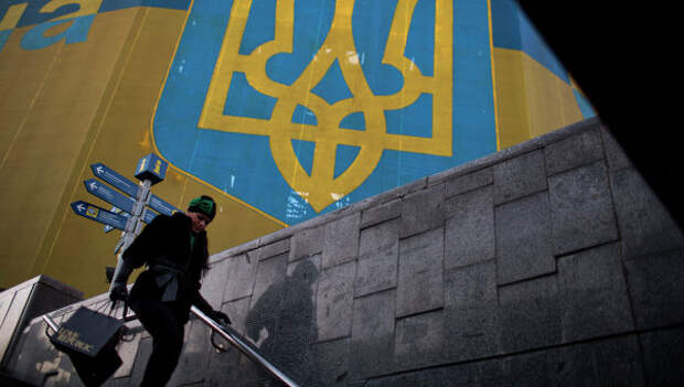 Женщина проходит мимо украинского флага. Архивное фото Женщина проходит мимо украинского флага. Архивное фото