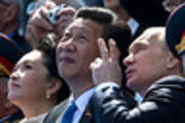 Russian President Vladimir Putin, right, gestures while speaking with Chinese President Xi Jinping, second left, watching the Victory Parade marking the 70th anniversary of the surrender of Nazi Germany in World War II, in Red Square, Moscow, Russia, Saturday, May 9, 2015. Xi's wife Peng Liyuan is at left. (AP Photo/Alexander Zemlianichenko, Pool)