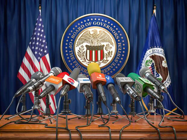 Microphones on a podium with the Federal Reserve seal on the wall behind.