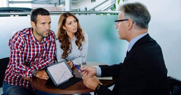 A couple discusses their options with a financial advisor in an office.