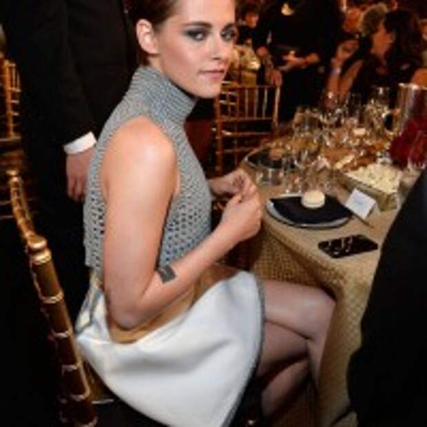 Kristen Stewart flared white skirt rising up gray crop top with pair of Casadei shoes