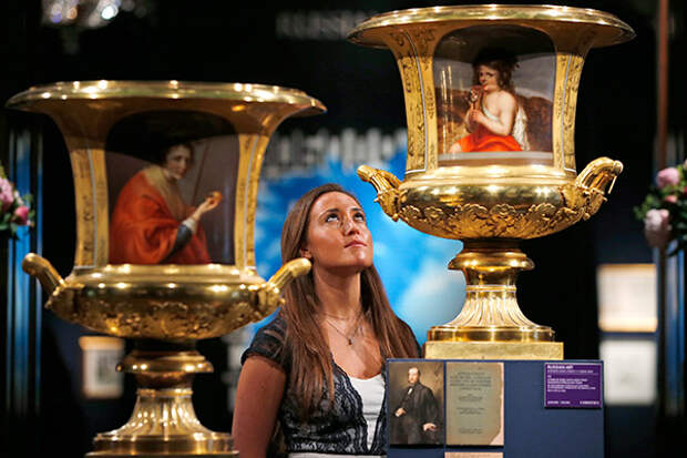 An auction house employee poses for the photographers behind a pair of rare and large two-handled porcelain vases by the Imperial Porcelain factory in St Petersburg, made during the period of Nickolas I, during a photo op ahead of an auction in central London, Friday, May 30, 2014.