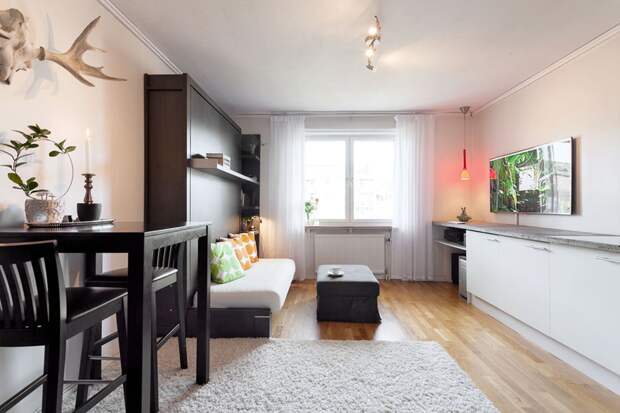 В такую маленькую студию и гостей не стыдно пригласить. Стильно обустроили 22 кв.м и интересно спрятали кровать