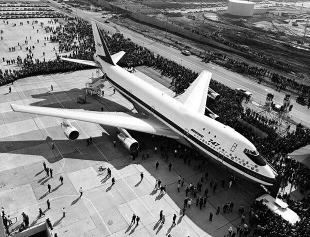 A black-and-white photo of a Boeing 747 on display outside. There are people all around the plane.