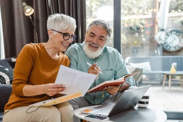 Two people at home smile while looking at douments.