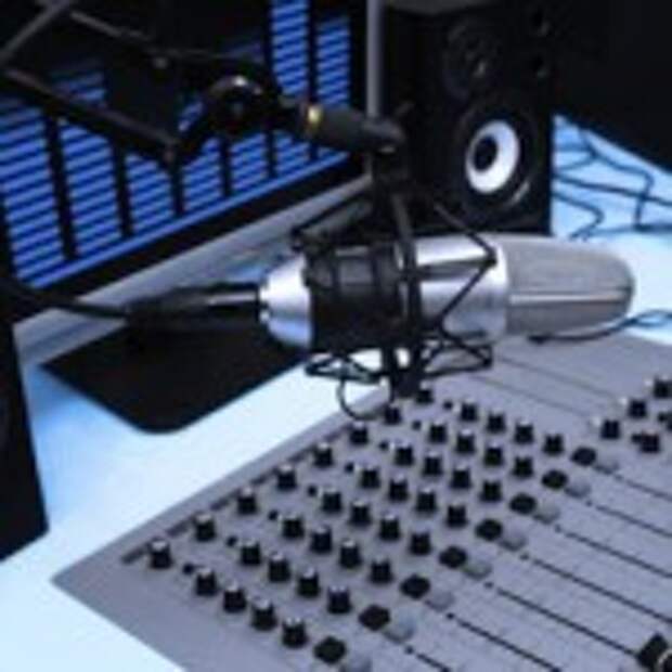 A mic in front of the control panel and screen in broadcasting studio