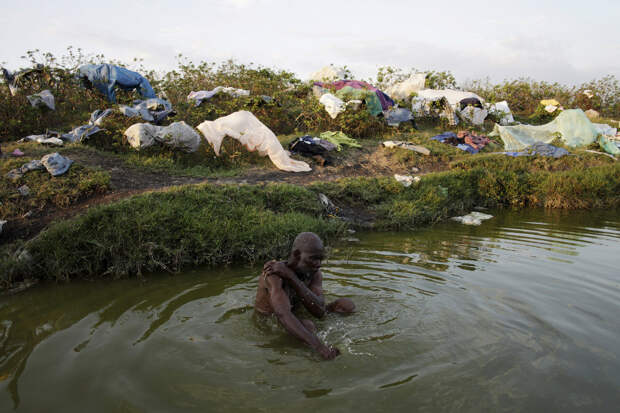 Прием ванны в грязном пруду недалеко от Порт-о-Пренс