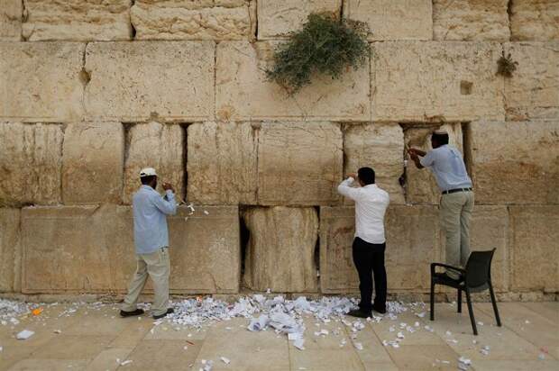 Работники чистят трещины в Стене Плача от записок, оставленных израильтянами и многочисленными туристами, чтобы освободить место для новых