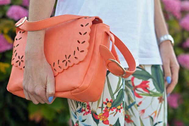 White tee, tropical print trousers, peach bag
