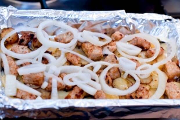 В форму с картошкой выкладываем мясо, выливаем масло, которое осталось в сковородке. Выкладываем колечки лука.