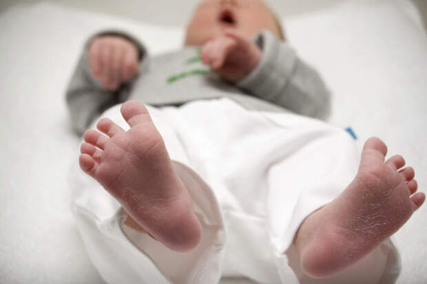 soles of a crying baby on a white towel
