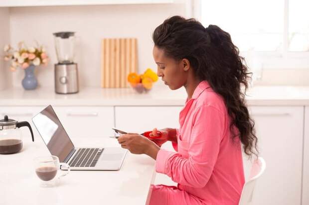Woman sitting in front of her laptop cutting up a credit card.