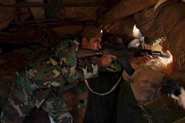 A member of the Kurdish Peshmerga forces holds his weapon while taking position in the town of Sinjar
