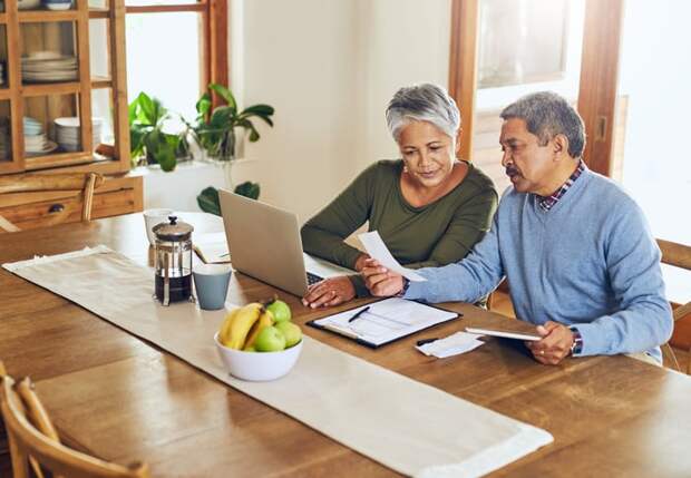 Couple looking at receipts in front of laptop.