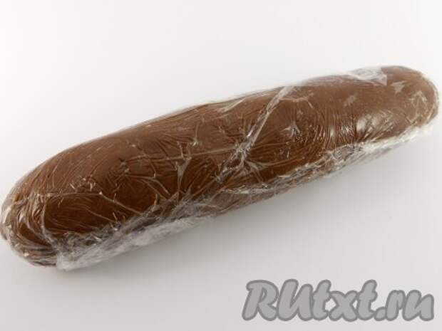 Рукой собрать крошку в один ком, а затем скатать длинную колбаску диаметром около 3 см. Выложить на пищевую пленку и плотно свернуть. Поместить тесто в холодильник на 30 минут.