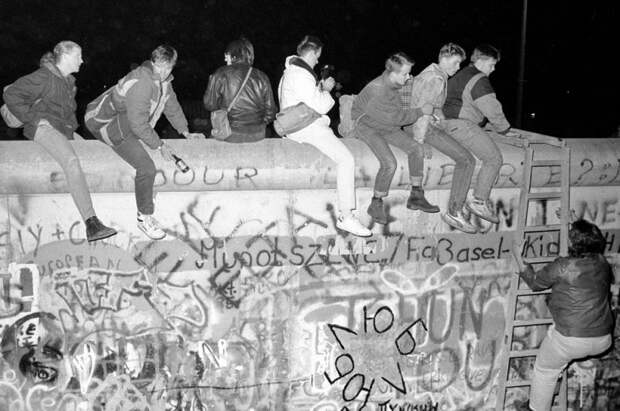 Жители Западной Германии сидят на Берлинской стене в районе Циммер-штрассе возле КПП «Чарли».