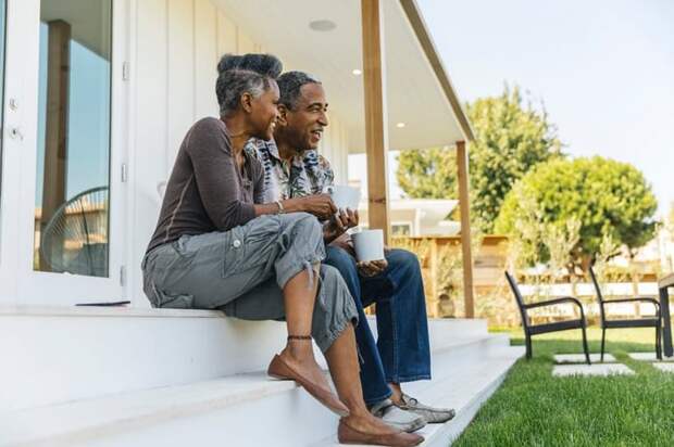 An older couple sit on their back porch, sip coffee, and enjoy the morning.