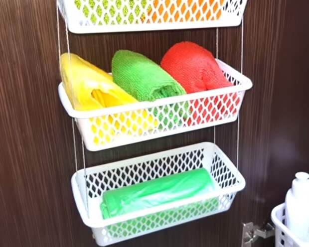 В связанных вместе корзинках удобно хранить легкие предметы на стенке шкафчика в ванной комнате.
