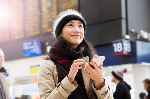 A visitor uses their smartphone as they wait for a train to arrive in a railroad station.