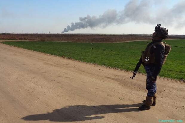 Солдат сил безопасности Ирака наблюдает, как дым поднимается от нефтяного месторождения Хуббаз к западу от северного города Киркук.