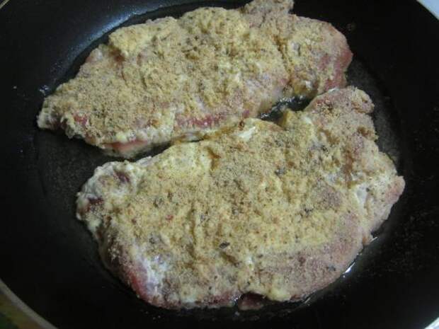 Запанированное мясо выложить на раскаленную сковороду. пошаговое фото этапа приготовления свиных отбивных