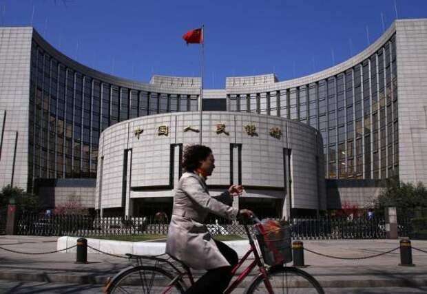 A woman rides past the headquarters of the People's Bank of China, the Chinese central bank, in Beijing, April 3, 2014.   REUTERS/Petar Kujundzic/Files