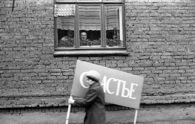 Женщина с плакатом спешит на первомайскую демонстрацию. Новокузнецк, 1 мая 1983 года. СССР, ностальгия, фото